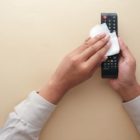 A woman cleaning a TV remote