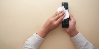 A woman cleaning a TV remote