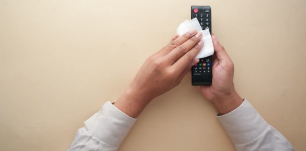 A woman cleaning a TV remote