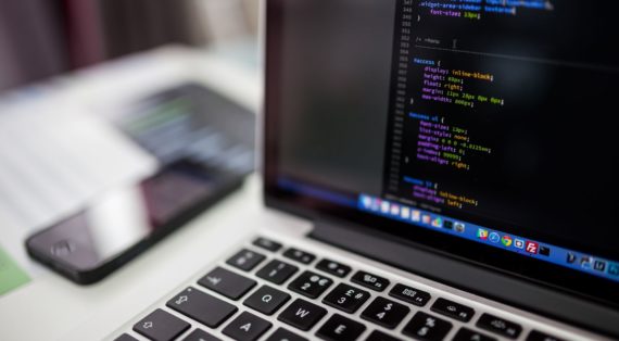 Macbook showing prorramming code partially on the screen